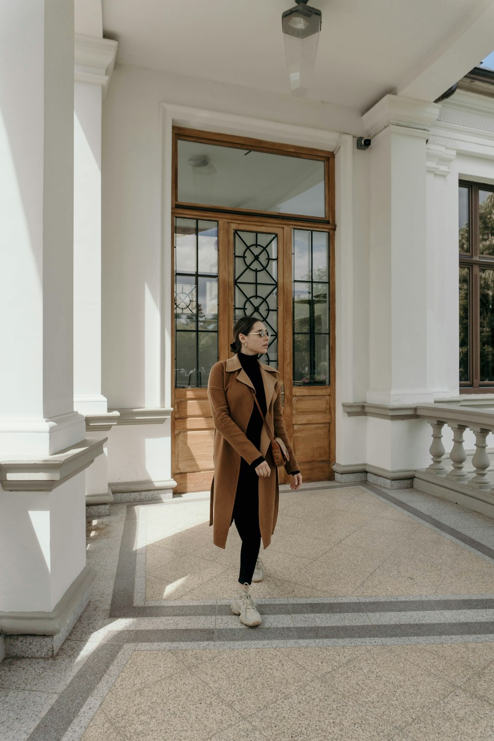 woman in brown coat standing near brown wooden door