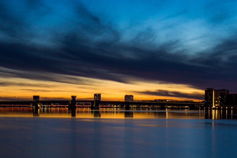 city skyline across body of water during night time