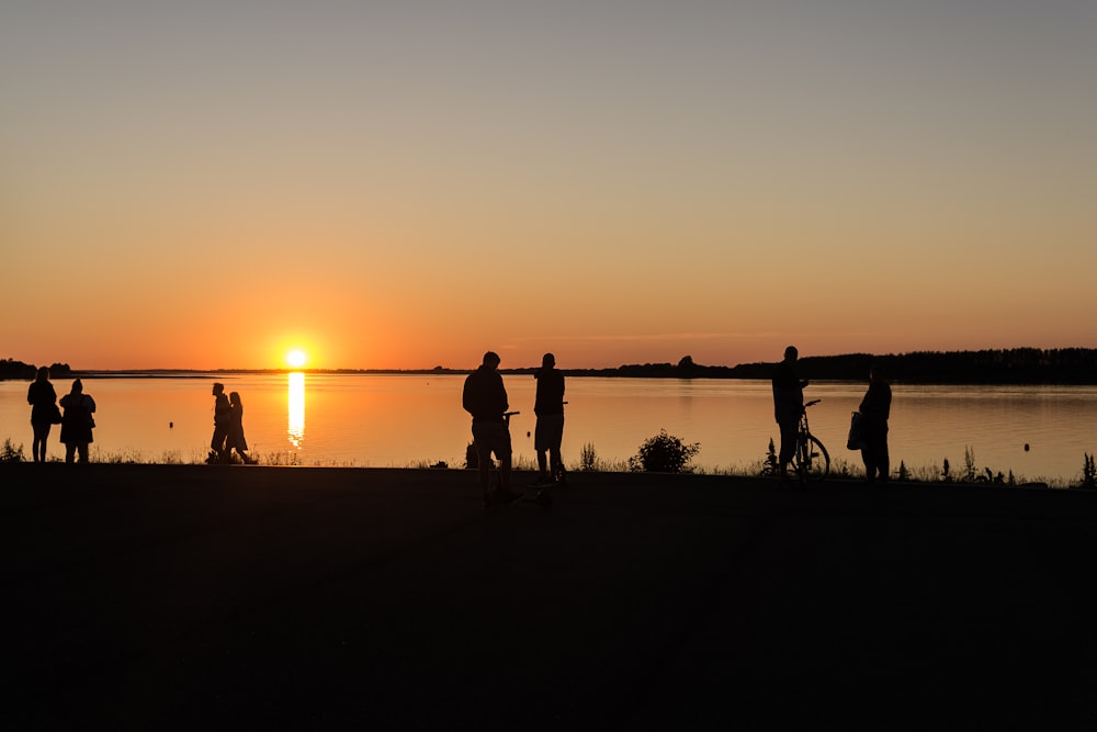 Silueta de personas que caminan en la playa durante la puesta del sol