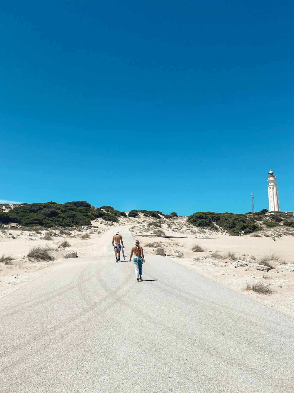 man in blue shirt and blue denim jeans walking on gray sand during daytime