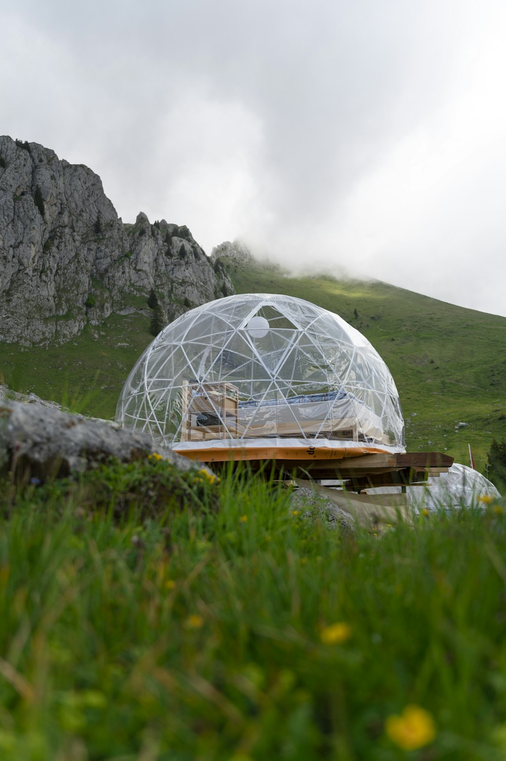 white and brown dome tent on green grass field near mountain during daytime