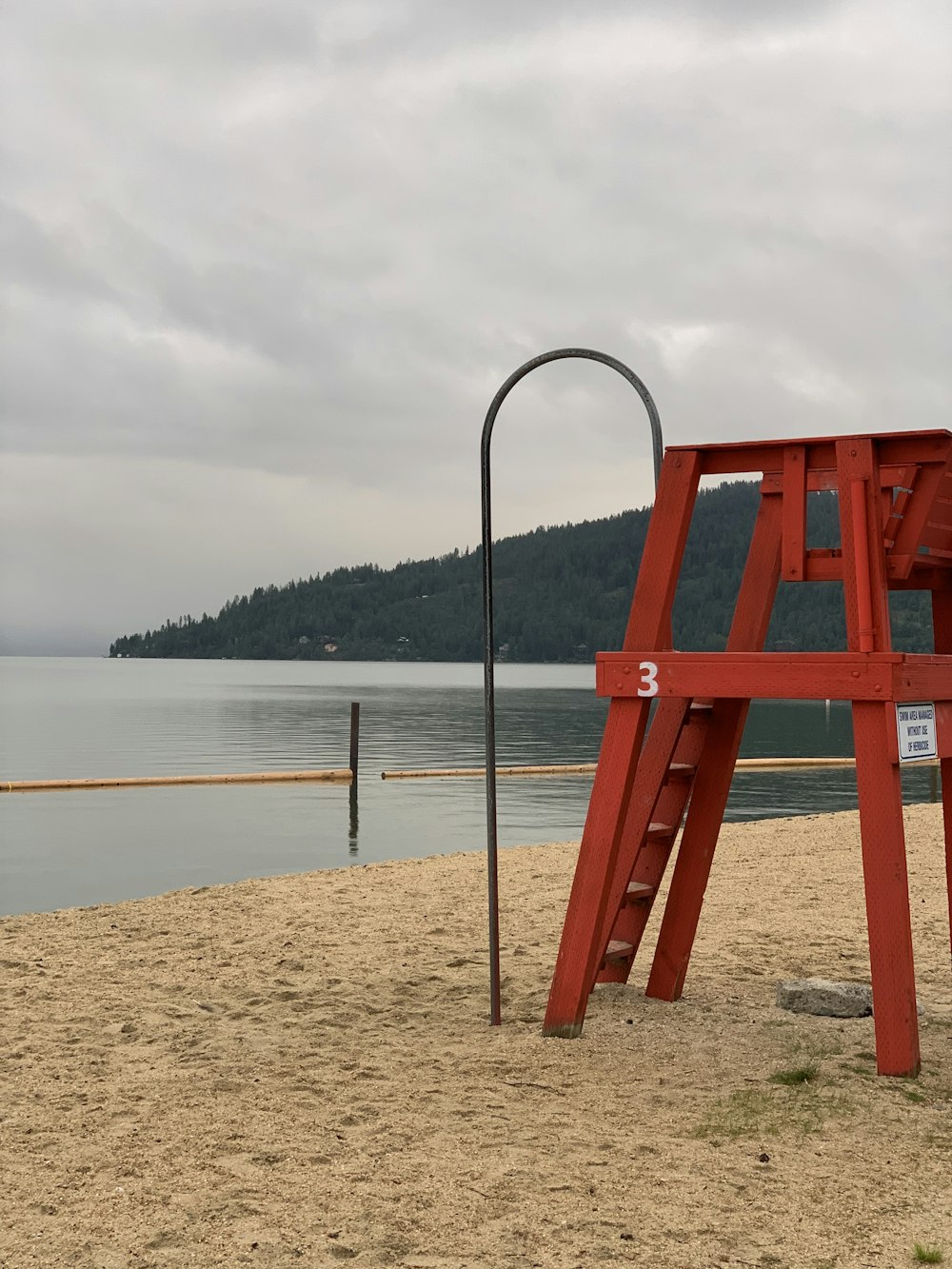 red metal stand on brown sand near body of water during daytime