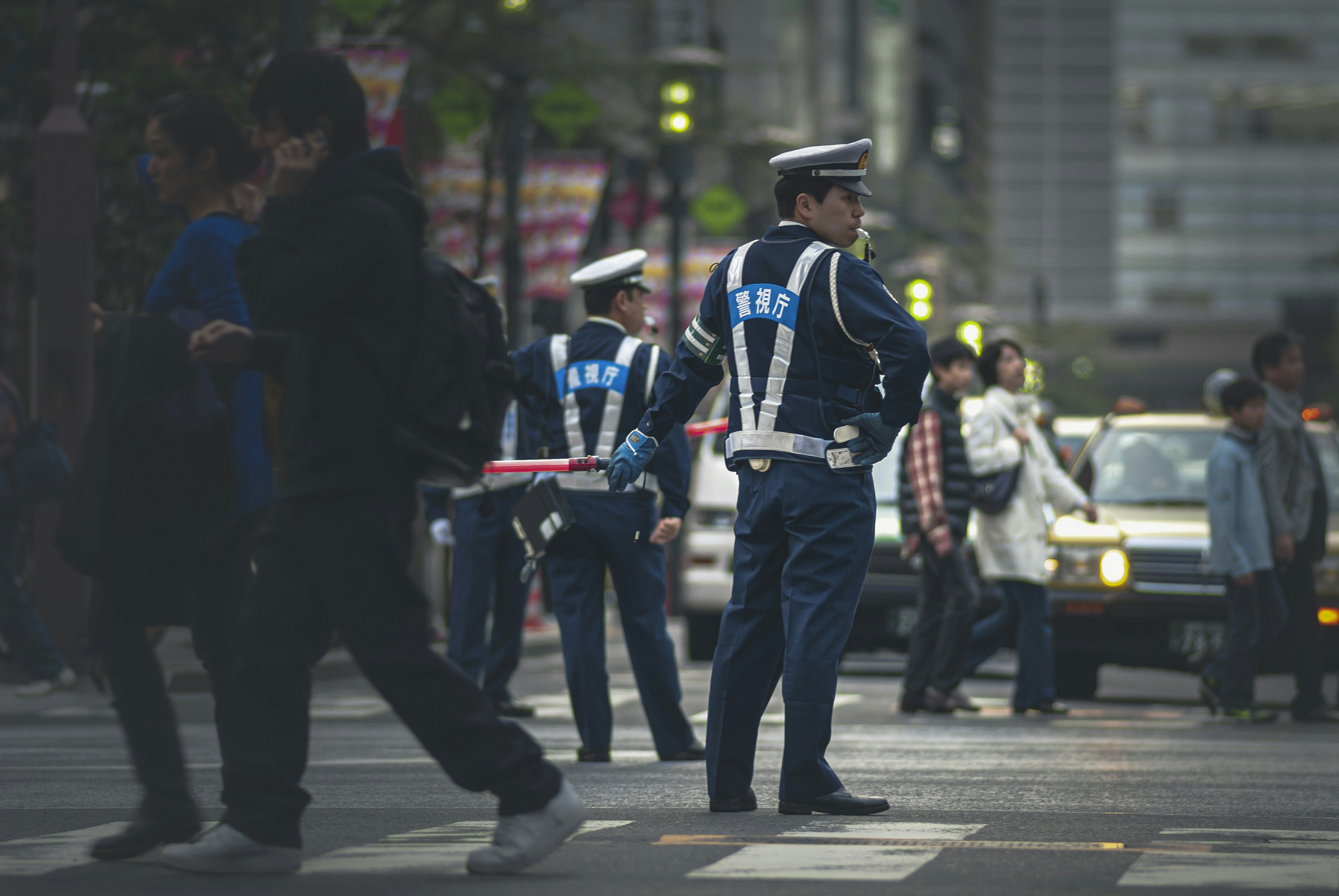 Emergency personnel in uniforms guiding people down a street away from damaged buildings
