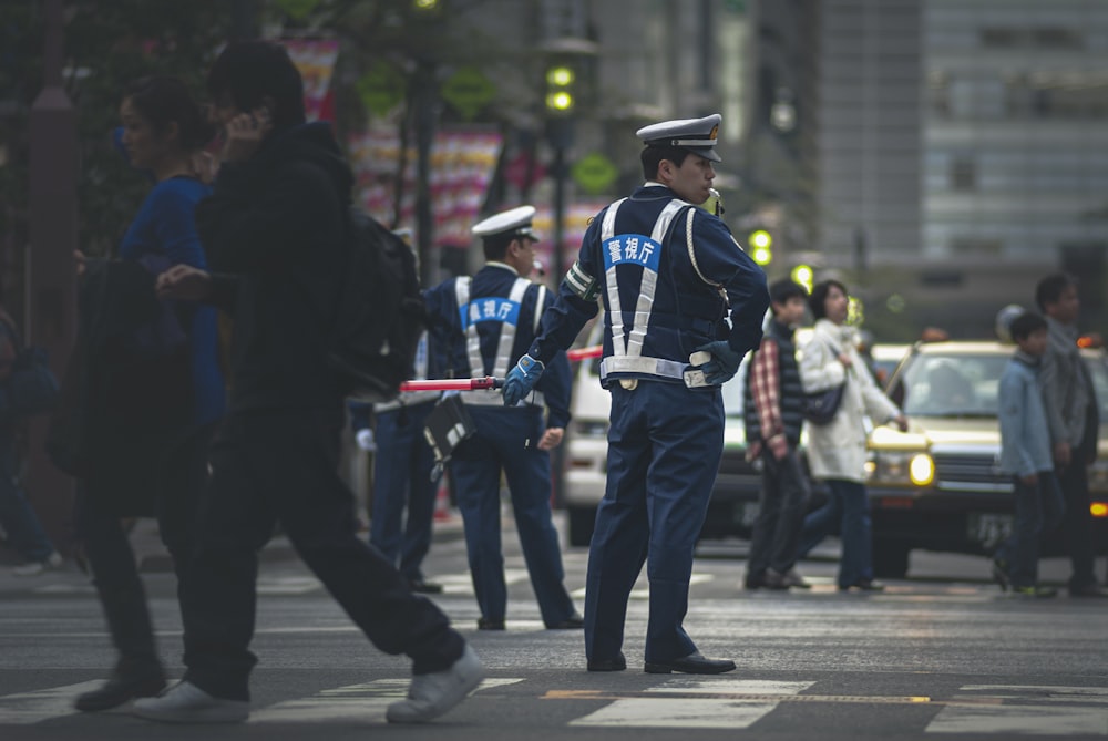 昼間、灰色のアスファルト道路に立つ青と白の警官の制服を着た男