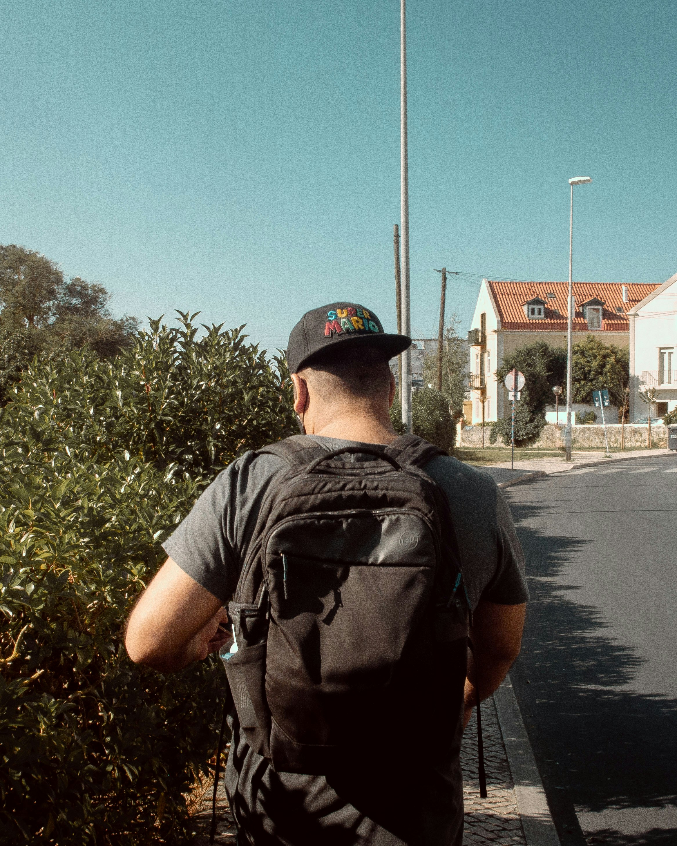 man in black t-shirt and black backpack standing on road during daytime