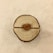 A wooden slice with concentric rings is placed on a light fabric background. At the center, a small heart-shaped piece with the word 'Love' engraved on it is embedded in the wood.