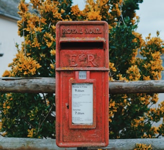 red mail box on brown wooden fence