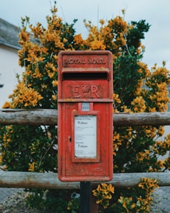 red mail box on brown wooden fence