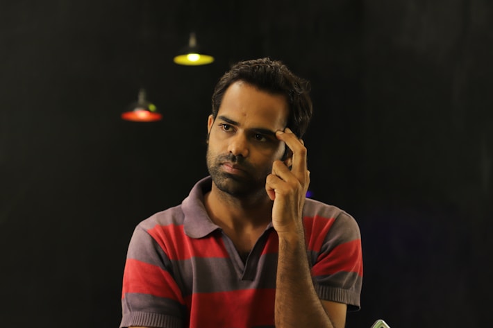 Contemplative man in a striped shirt holding a phone, representing career decision-making 