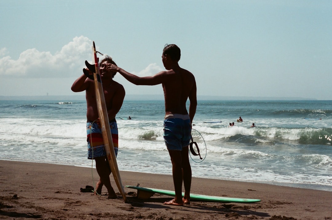 man in blue shorts holding brown wooden stick standing on beach during daytime