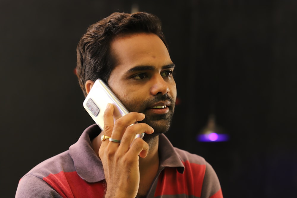 man in red and gray hoodie holding white smartphone