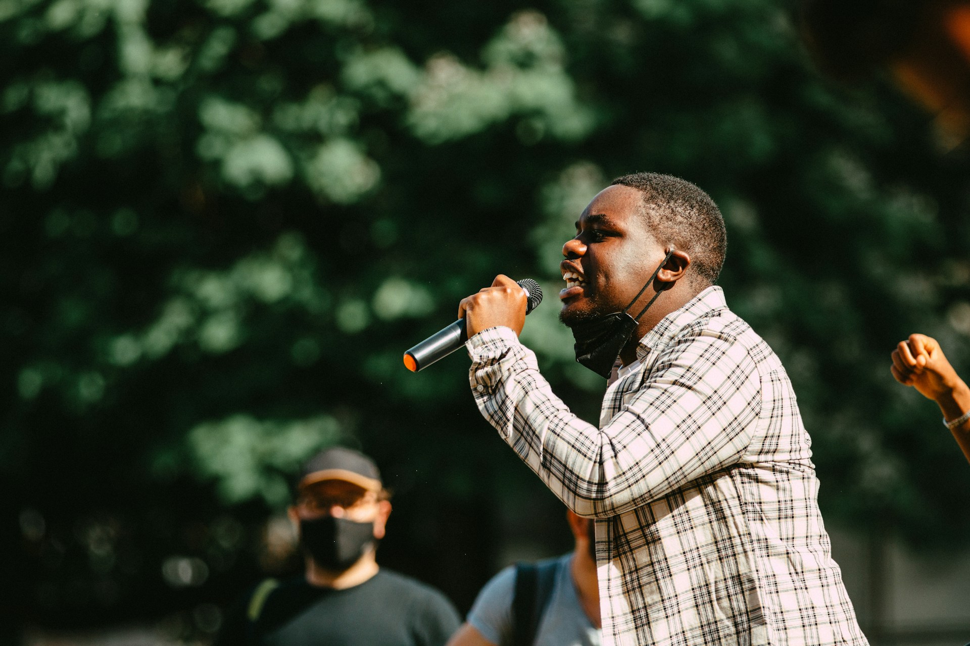 man in blue and white plaid dress shirt holding microphone