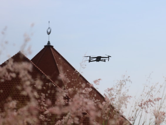 A professional drone flying over a residential rooftop during a clear day.