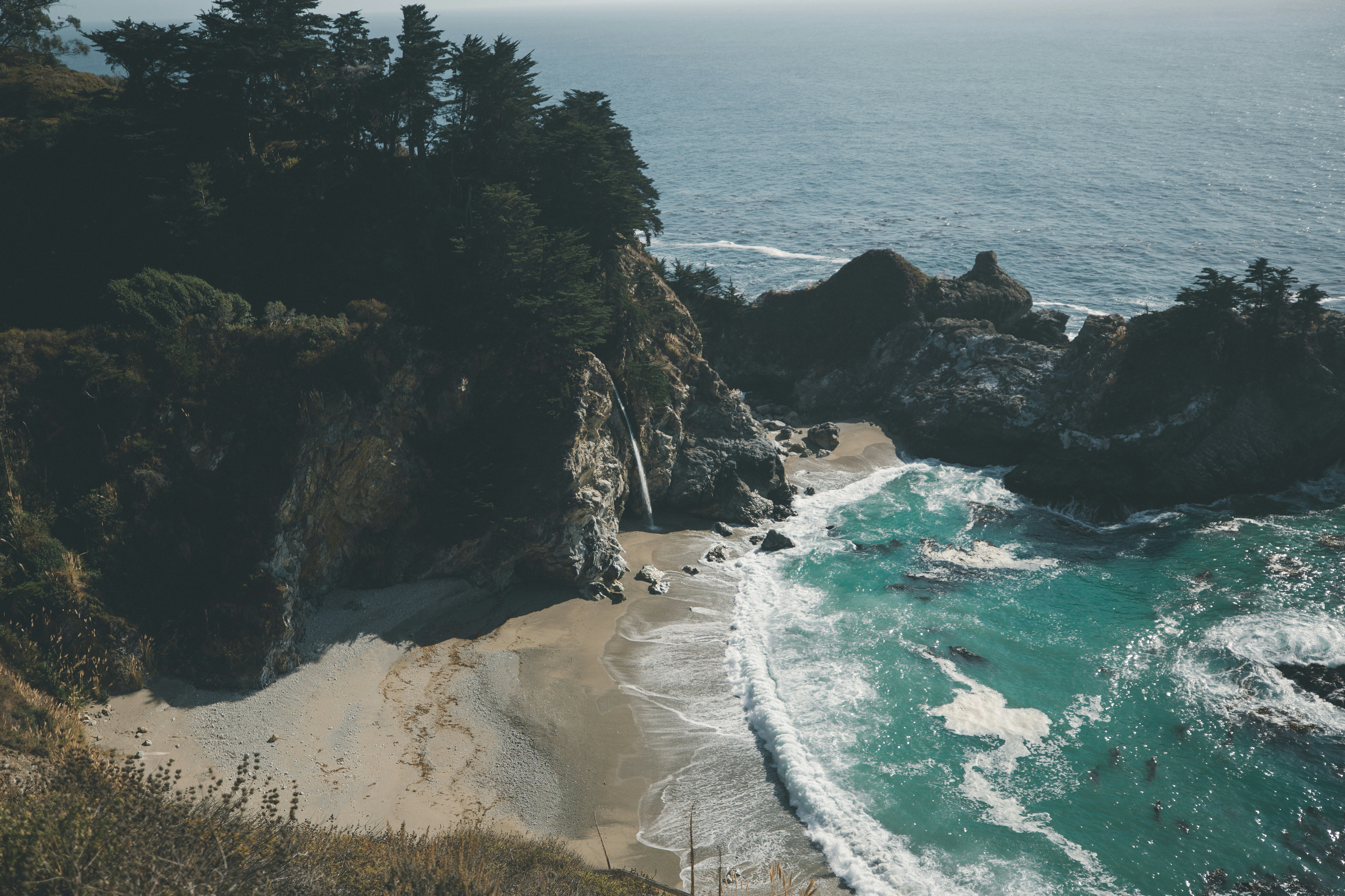 brown rocky mountain beside blue sea during daytime