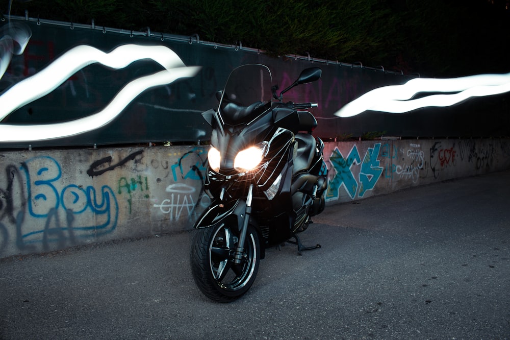 motocicleta preta estacionada ao lado da parede com grafite