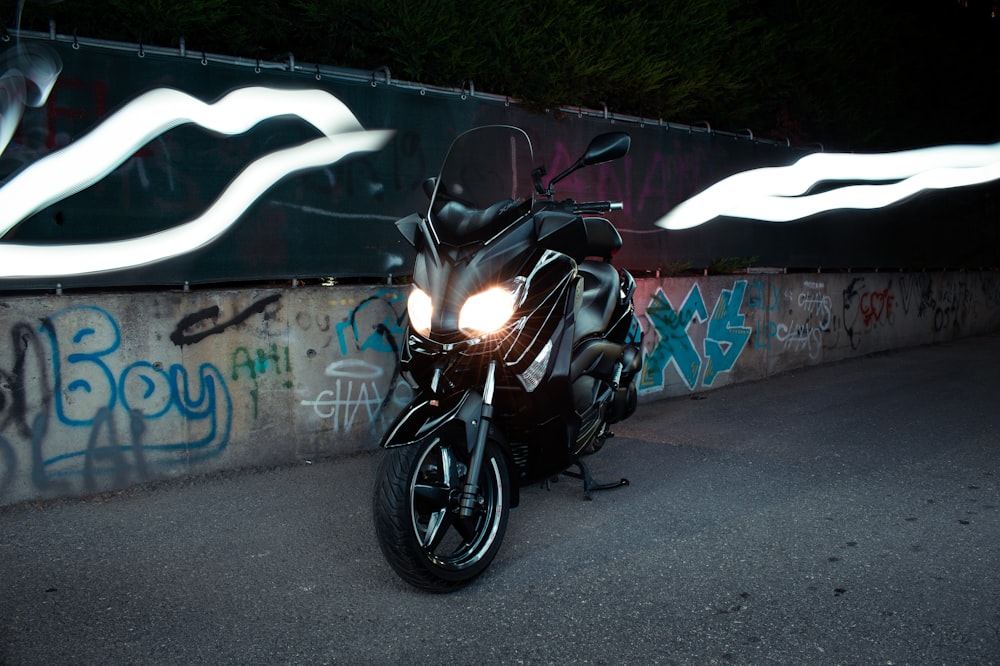 black motorcycle parked beside wall with graffiti