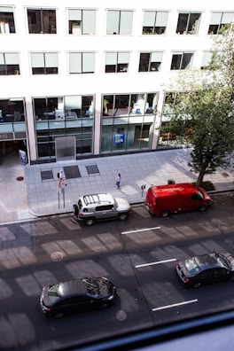 A city street with various cars available for rent parked along the curb.