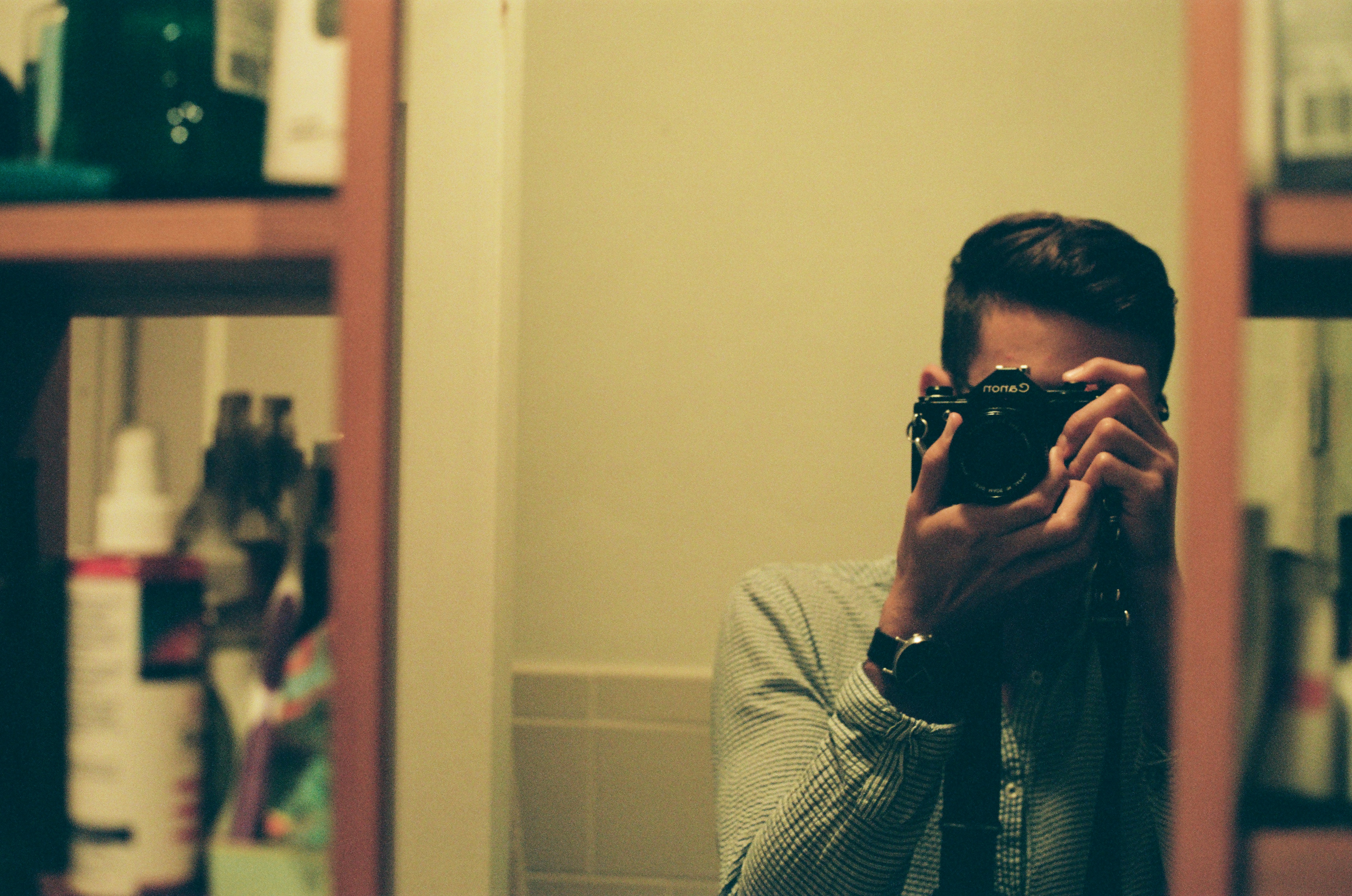 man in gray and white striped long sleeve shirt holding black dslr camera