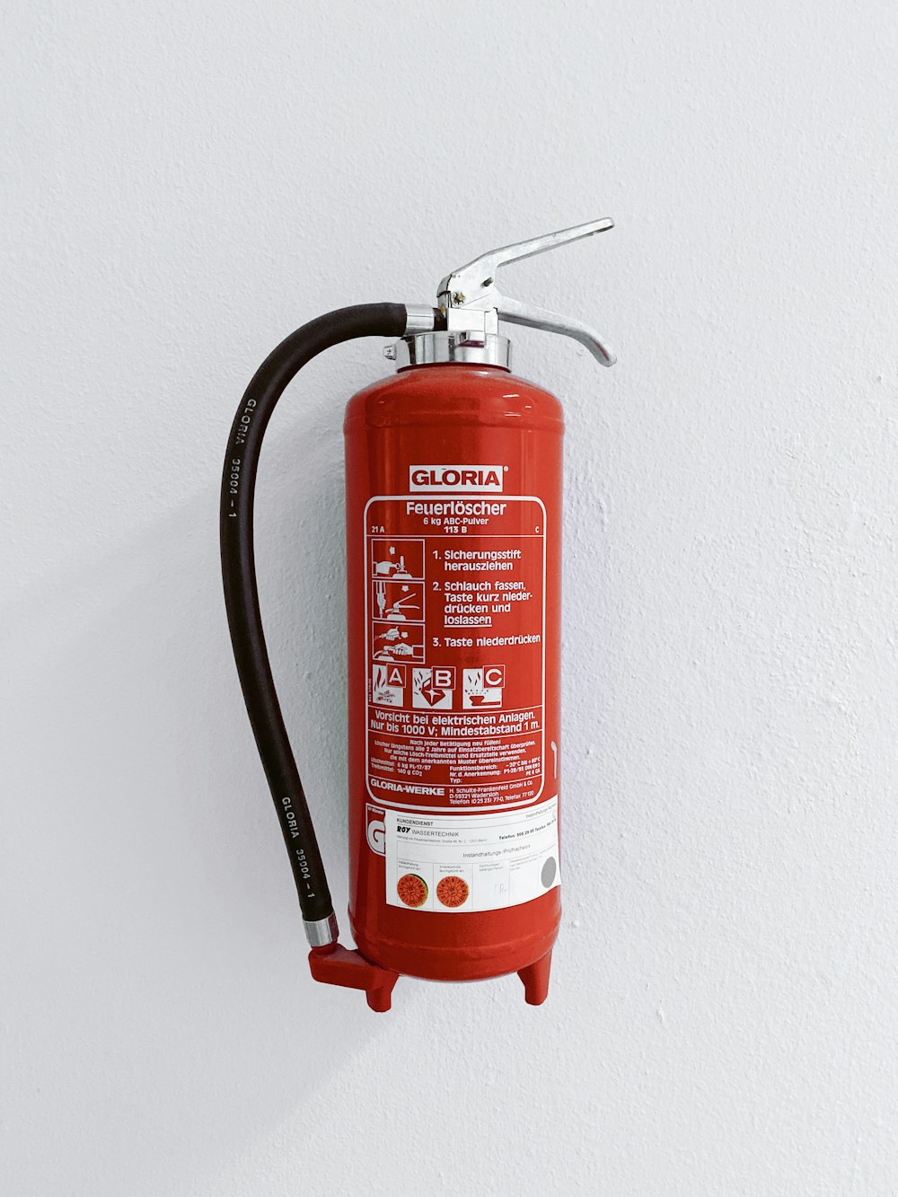 red fire extinguisher mounted on white wall