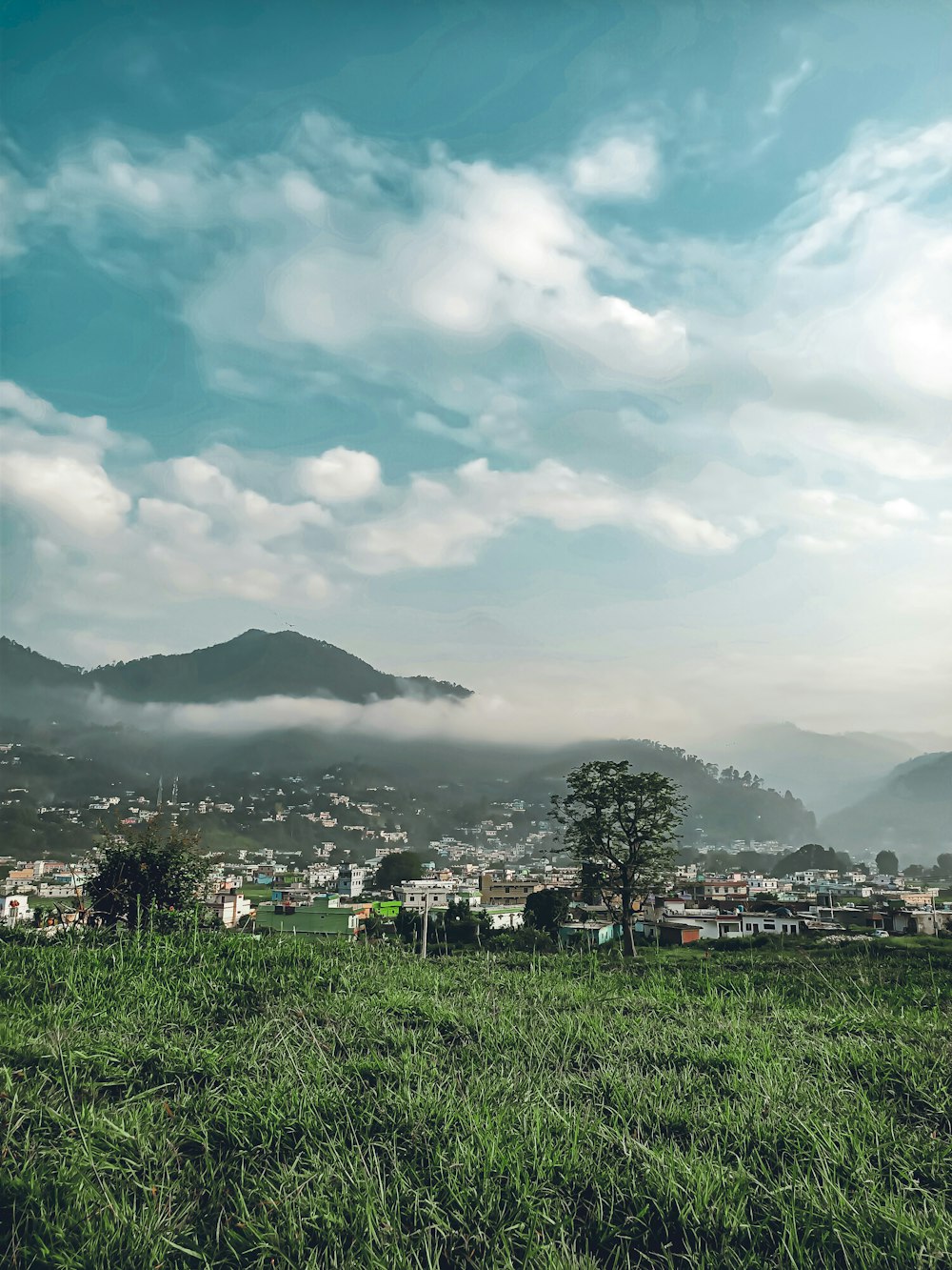 green grass field near mountain under white clouds during daytime