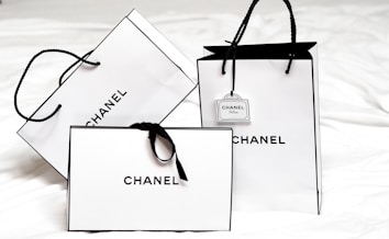 Three white shopping bags with black handles and bold black 
