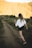 woman in white shirt and black shorts walking on dirt road during daytime