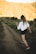 woman in white shirt and black shorts walking on dirt road during daytime