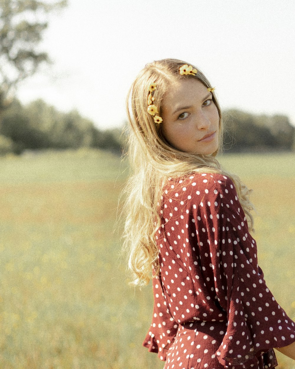 girl in red and white polka dot long sleeve shirt standing on green grass field during