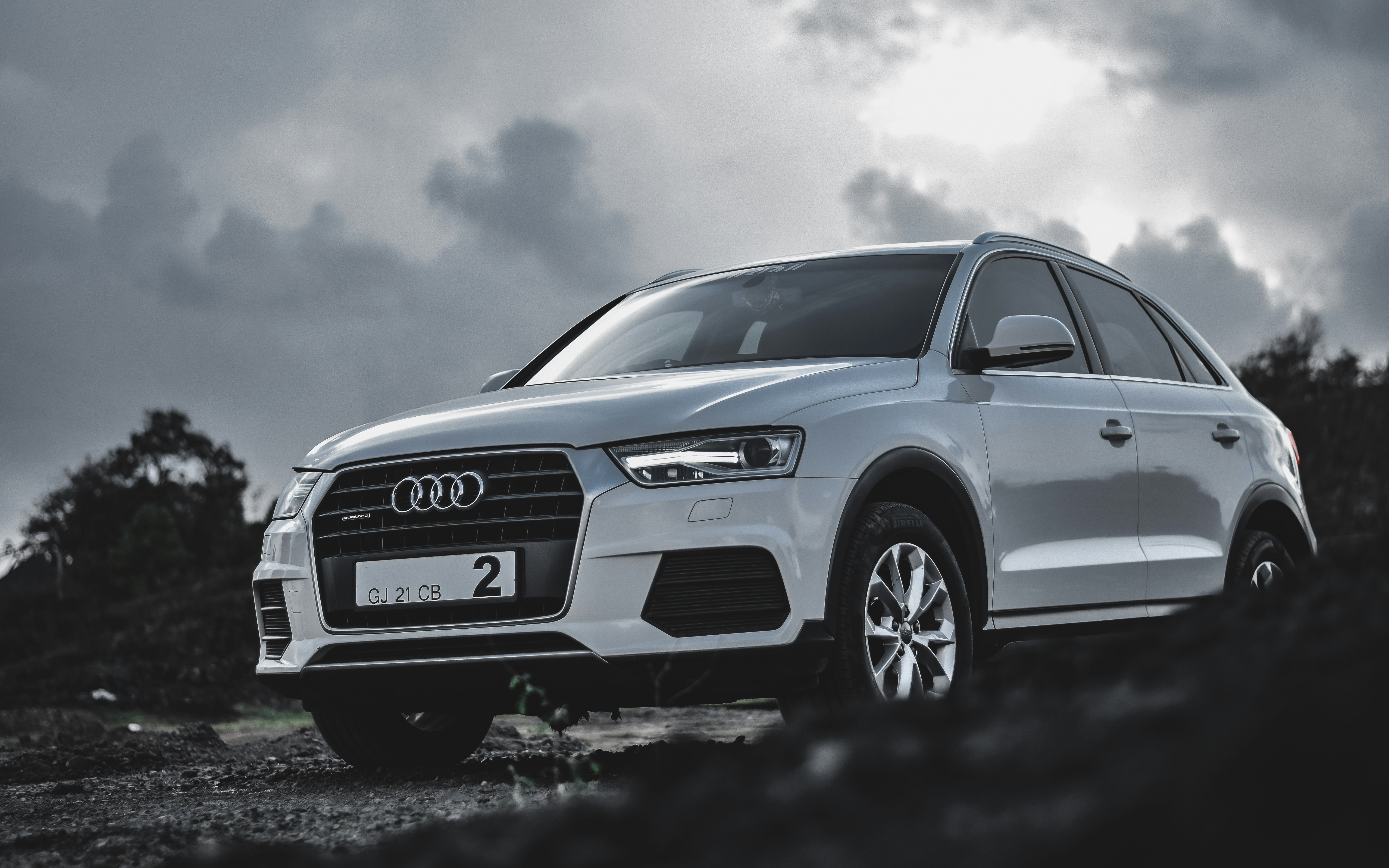 Audi Q3 compact SUV in white, elevated view, mountain road backdrop, clear sky