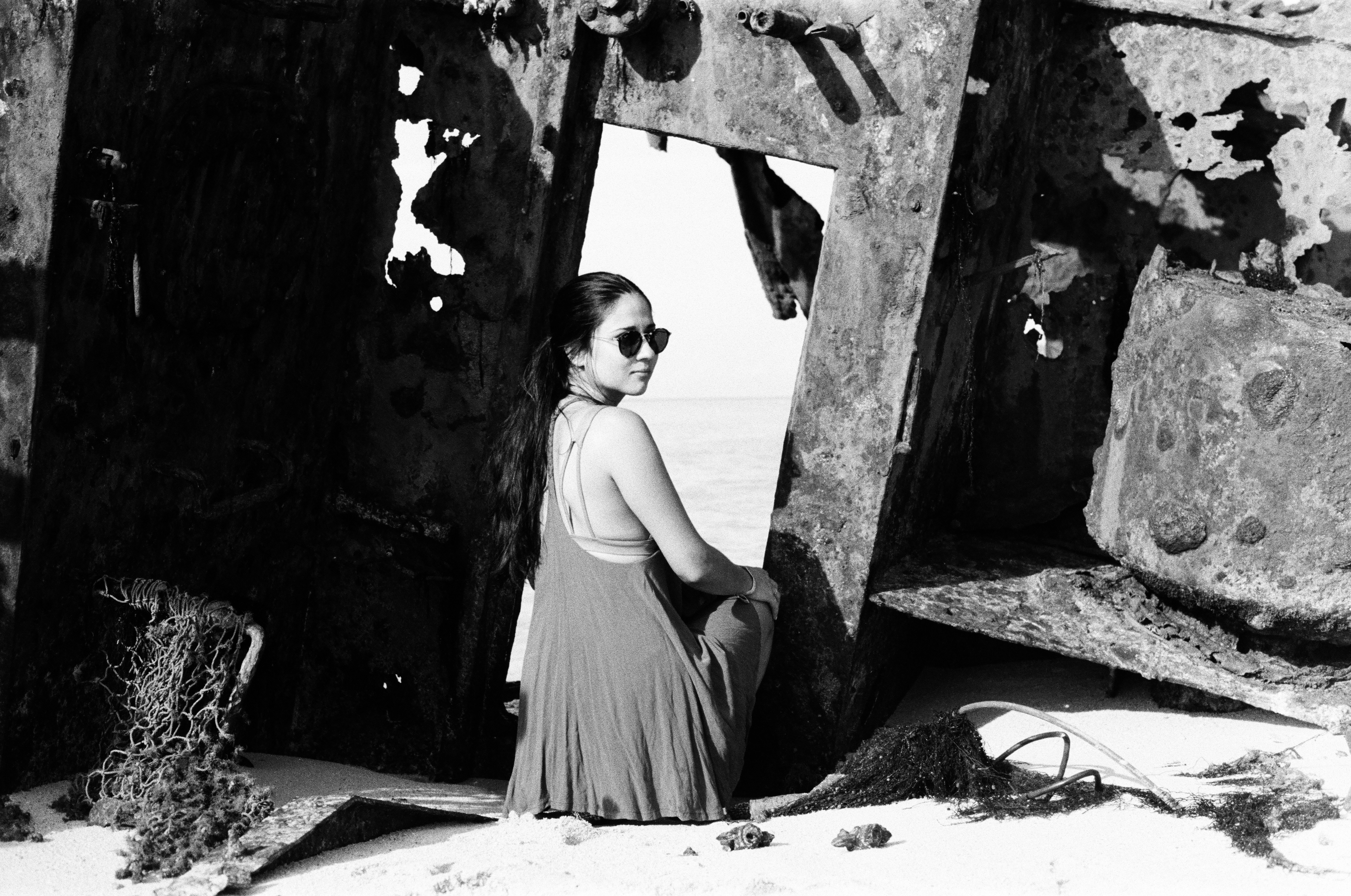 woman in black tank dress standing beside wall