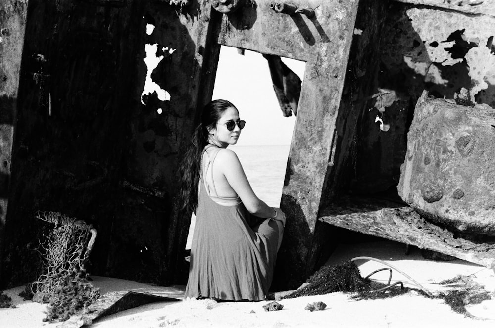 woman in black tank dress standing beside wall