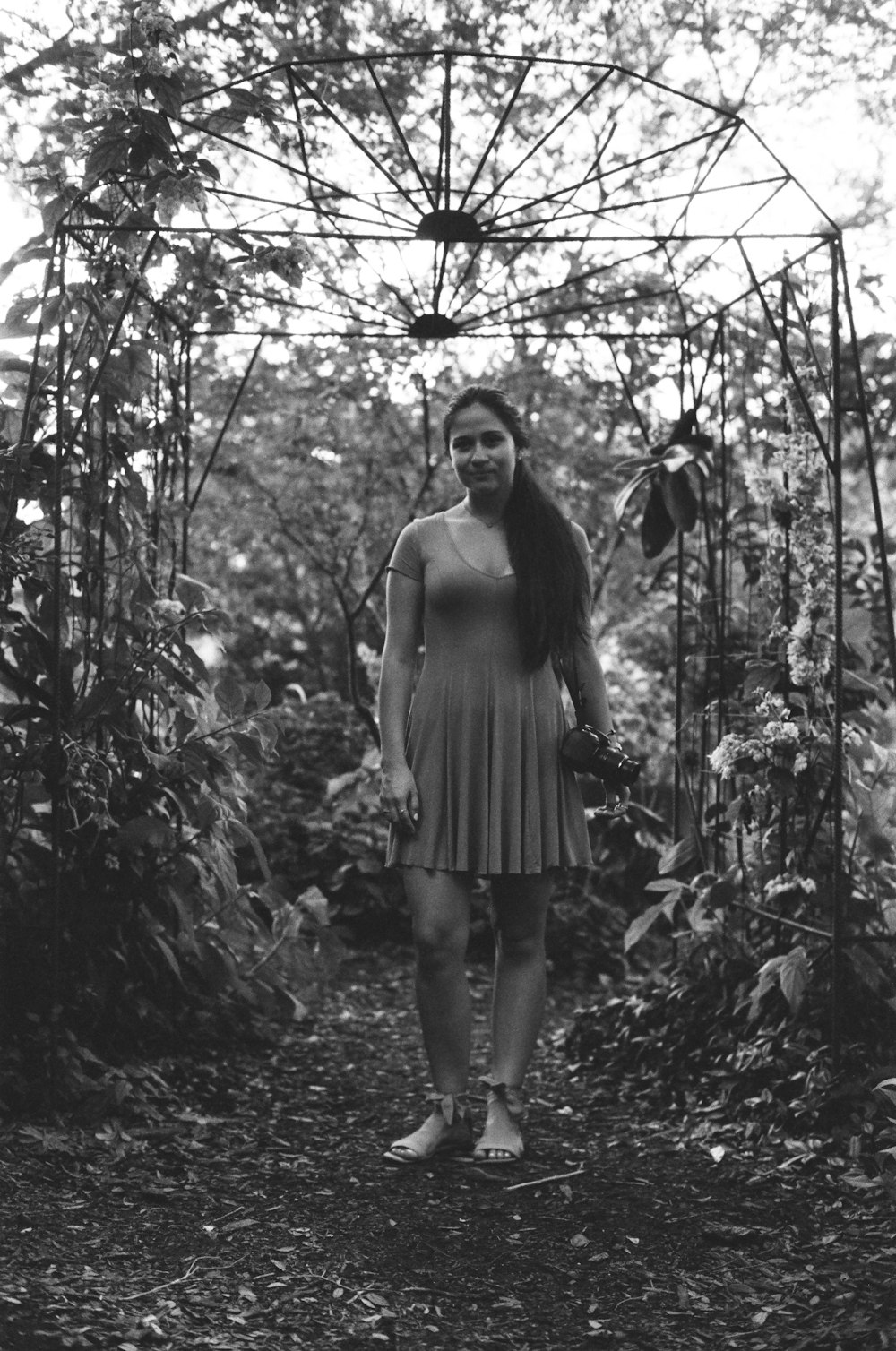 woman in white tank top and black skirt standing in the middle of the forest