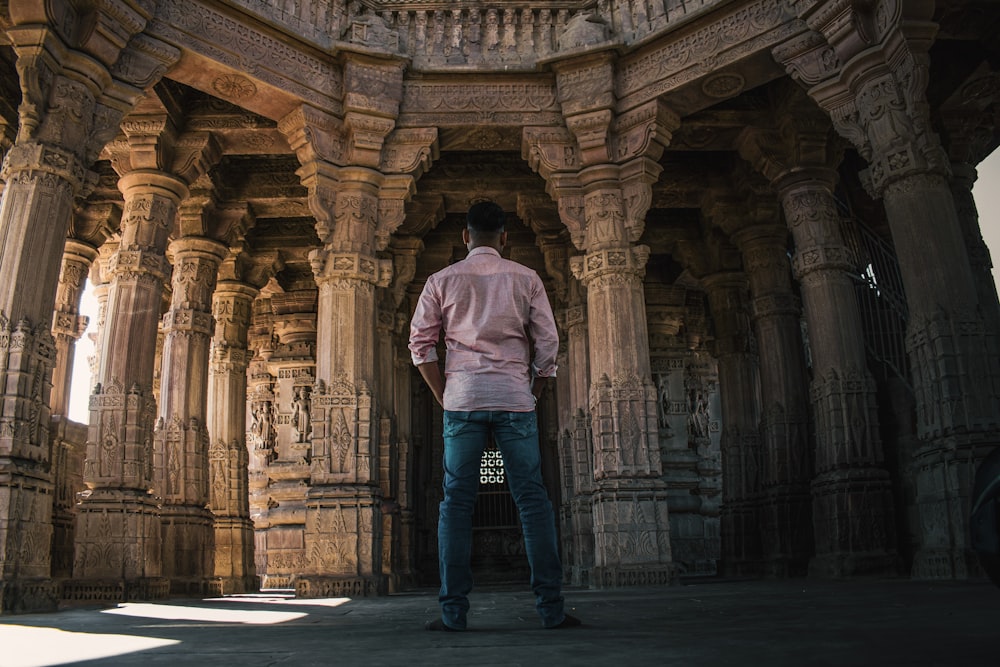 man in white hoodie standing in front of brown concrete building during daytime