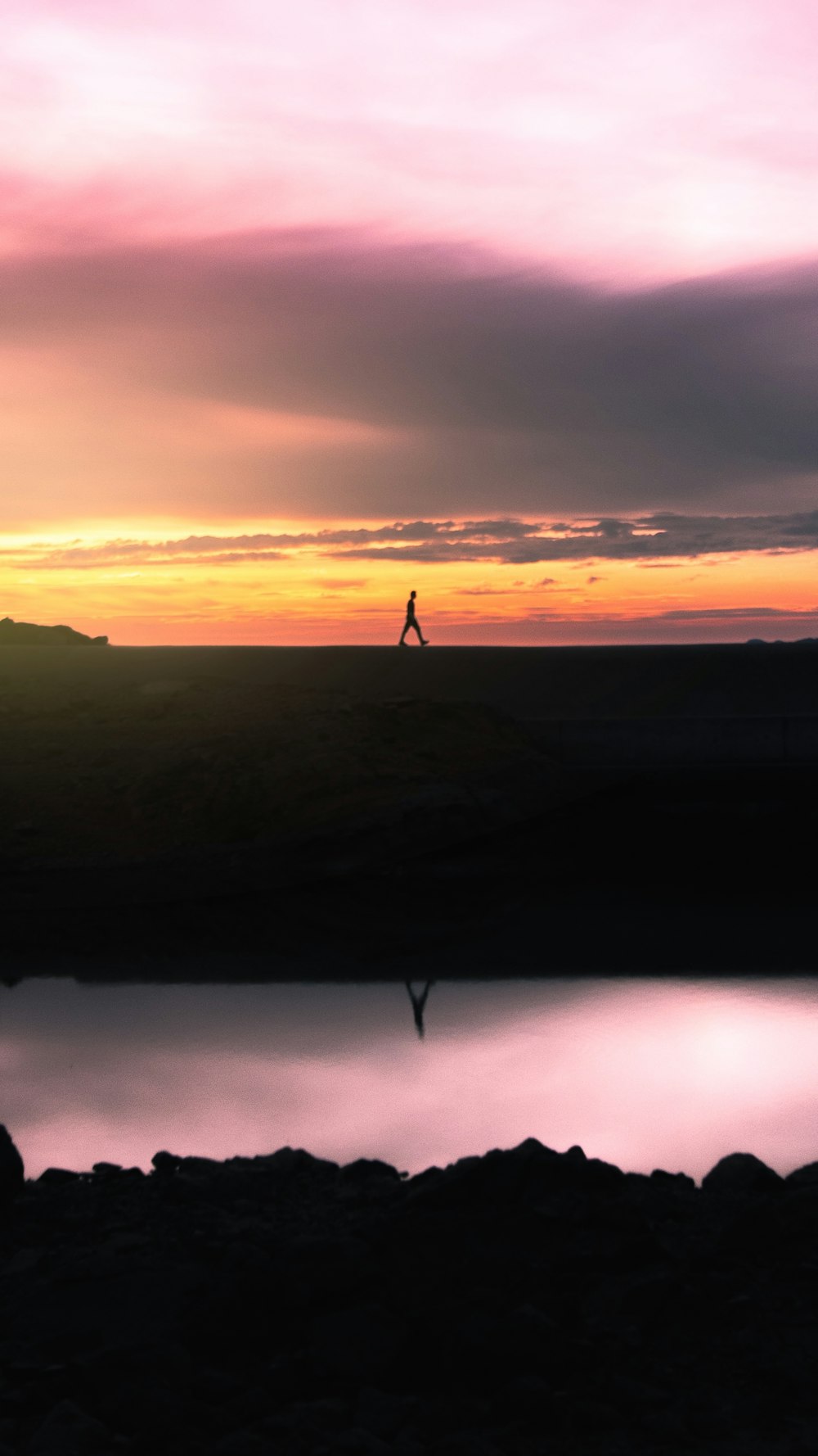 silhouette of person standing on hill during sunset