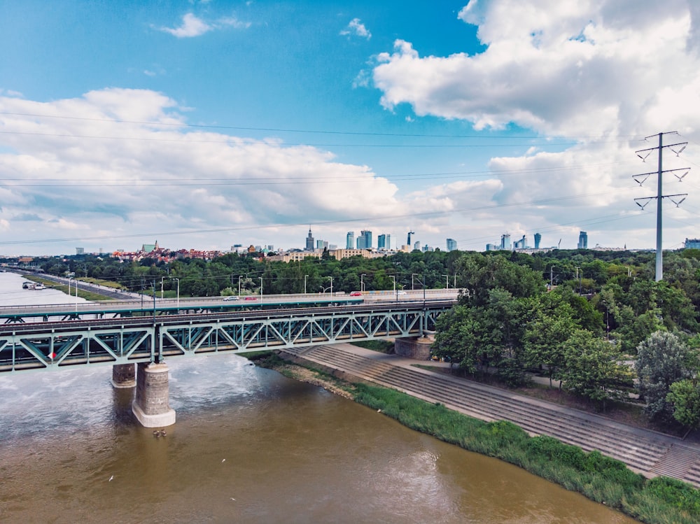 green metal bridge over river under blue sky during daytime