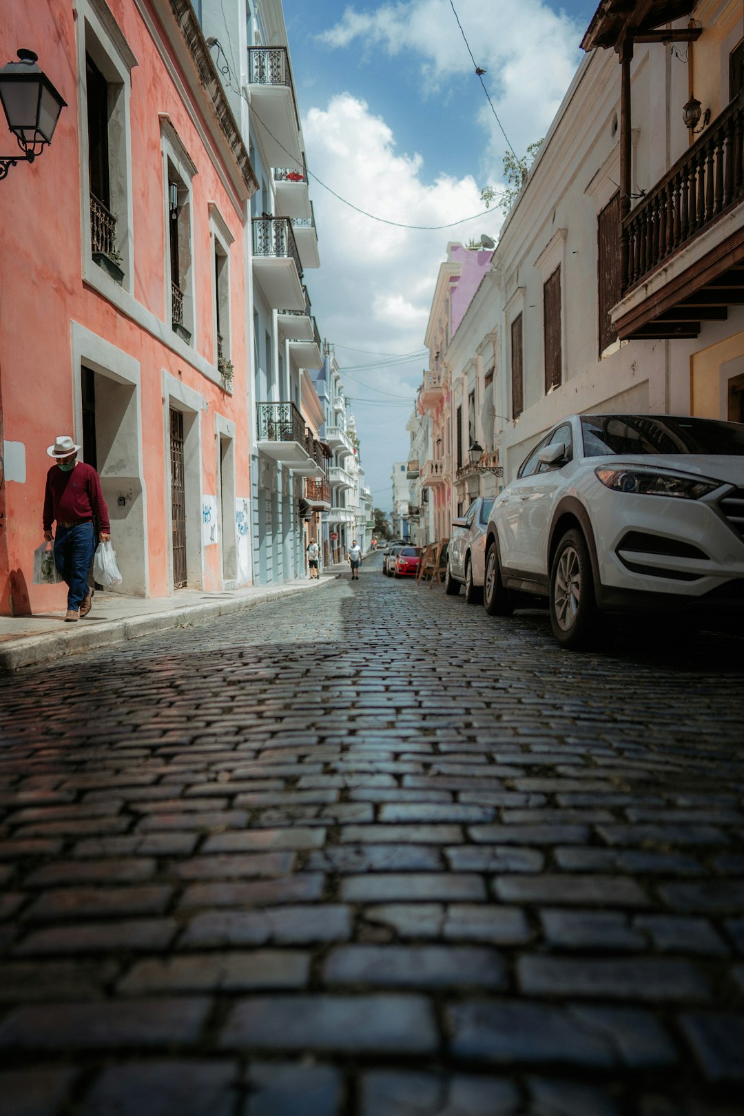 man in red jacket walking on sidewalk during daytime