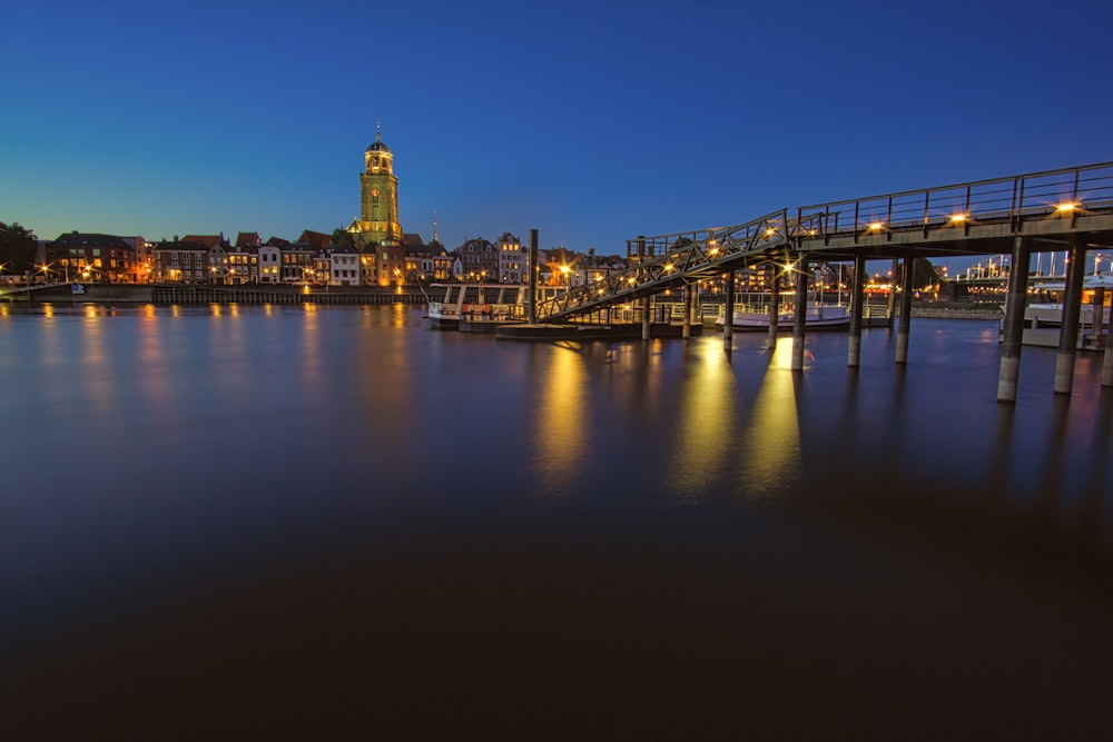 Puente sobre el agua cerca de los edificios de la ciudad durante la noche