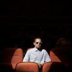 man in blue dress shirt wearing sunglasses sitting on brown chair