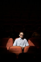 Un homme en blanc et avec des lunettes de soleil assis sur un strapontin
