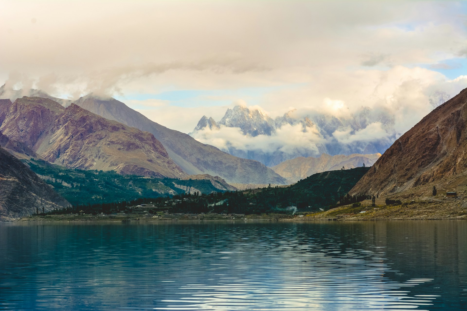 green and brown mountains beside body of water under white clouds during daytime