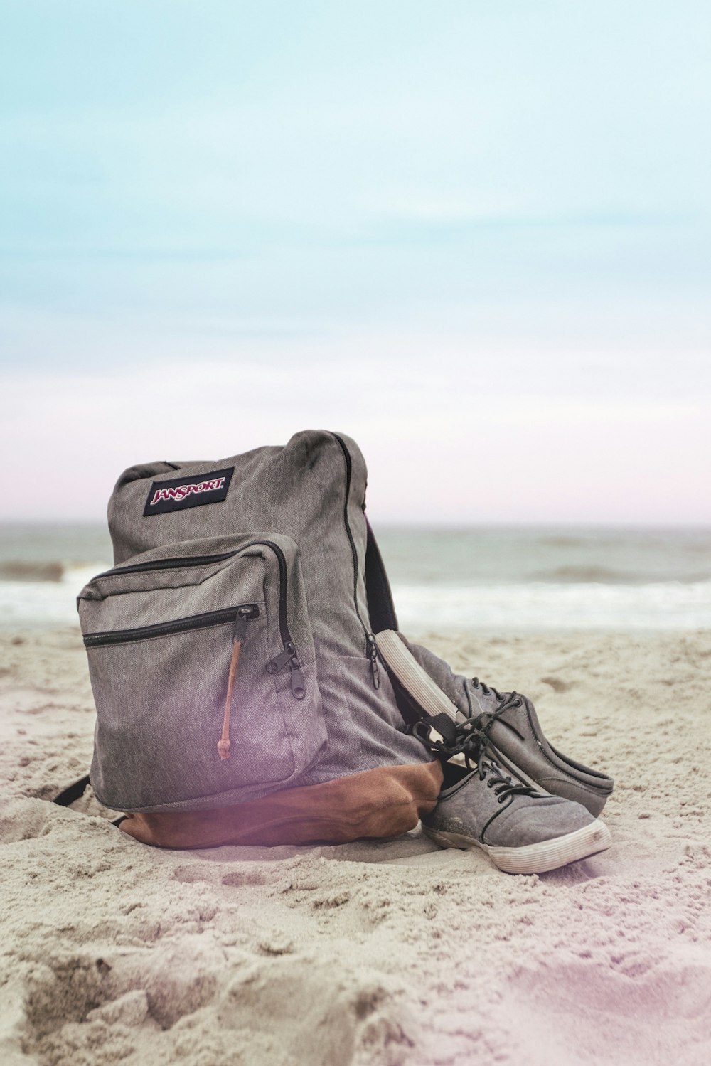 black and red nike backpack on brown sand near body of water during daytime