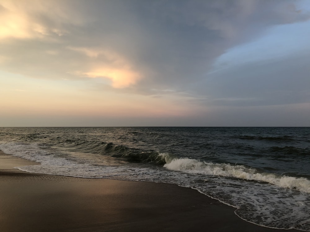 ocean waves crashing on shore during sunset