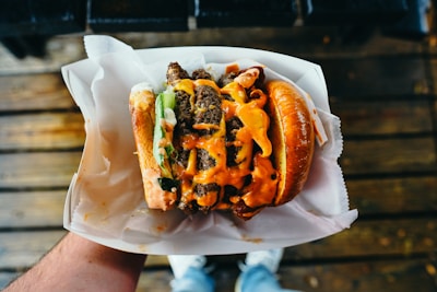 A juicy burger stacked high with fresh lettuce and tomato, wrapped in omg feast’s signature red and white paper.