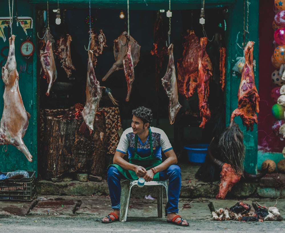 woman in blue shirt sitting on ground near red and white meat