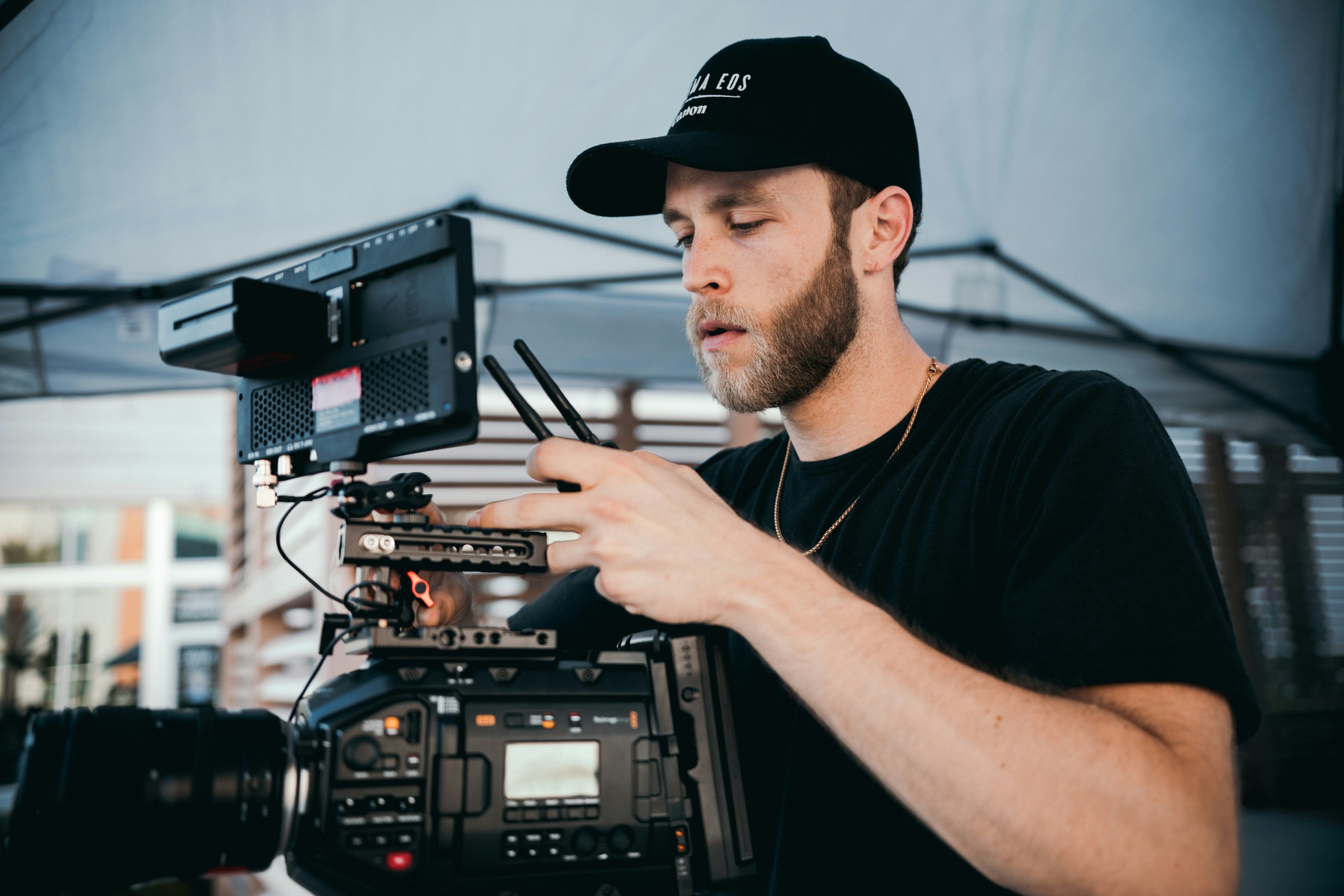 man in black crew neck t-shirt wearing black cap operating video camera