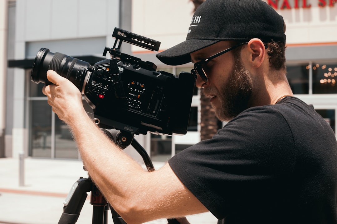 man in black t-shirt holding black dslr camera