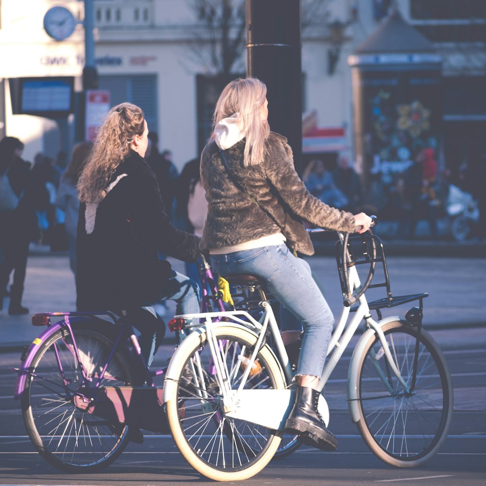 woman in black jacket and blue denim jeans riding on bicycle