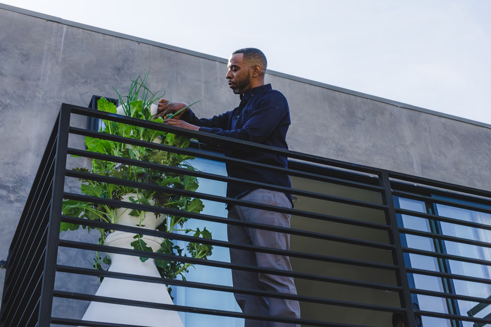 man in black jacket standing beside green plant during daytime