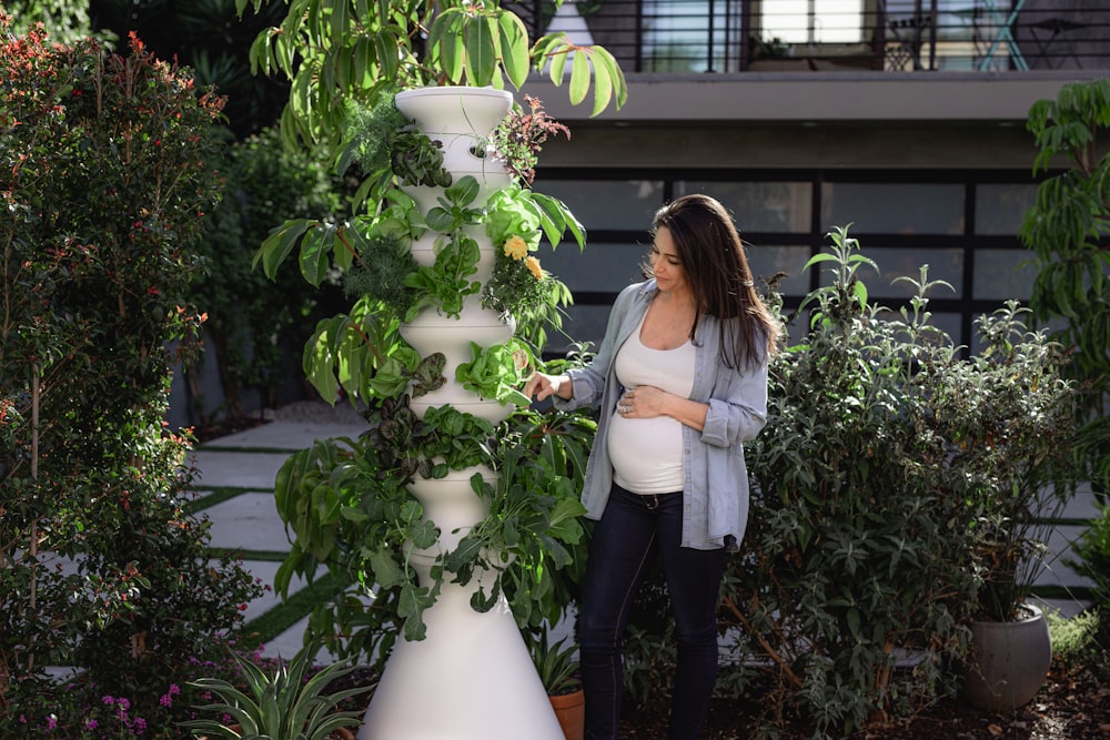 woman in white long sleeve shirt and black pants standing beside white flower