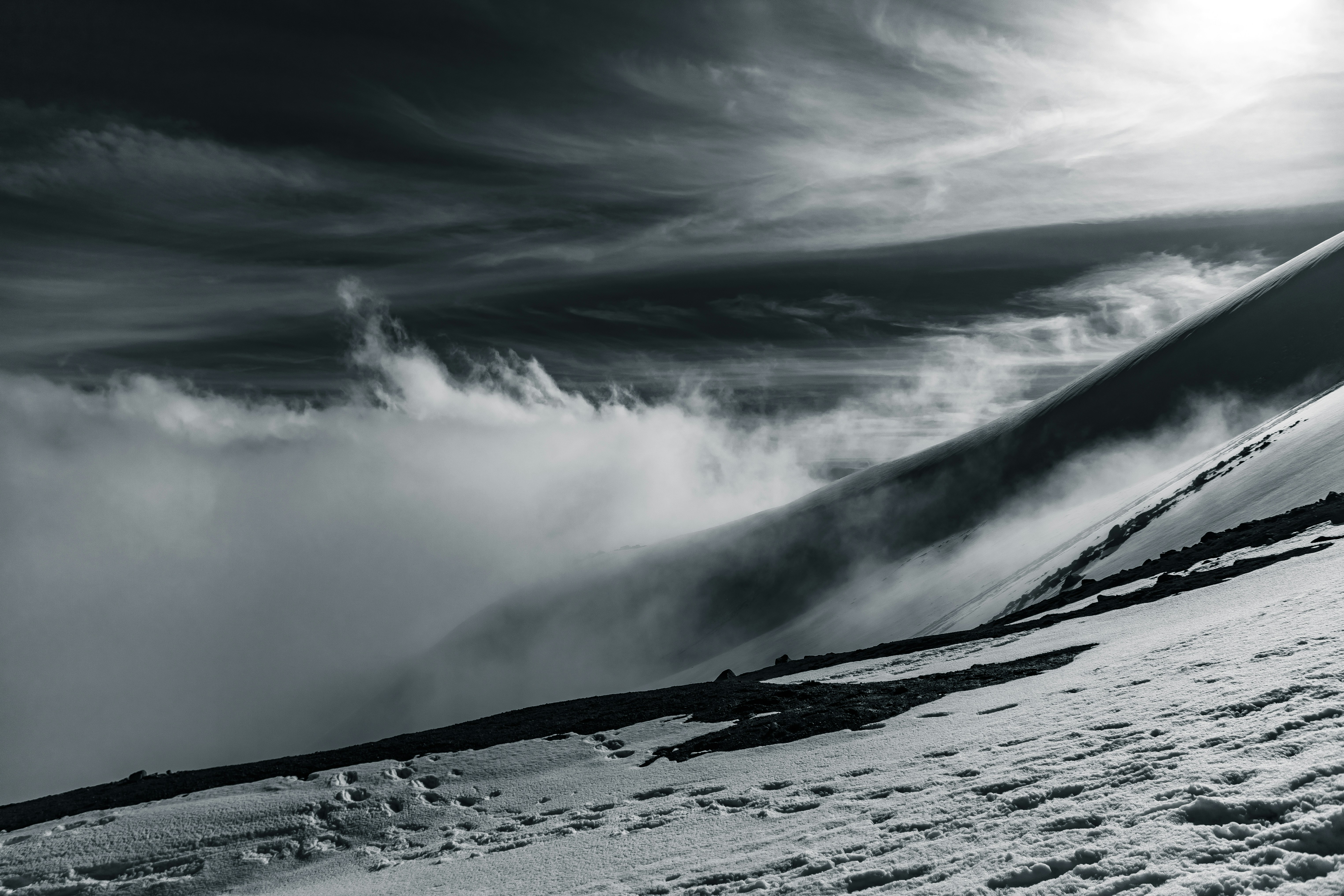 An image of clouds meeting a snowy hill. This shot was taken on the hike back down after summiting Mt. Saint Helens (June 2020). 